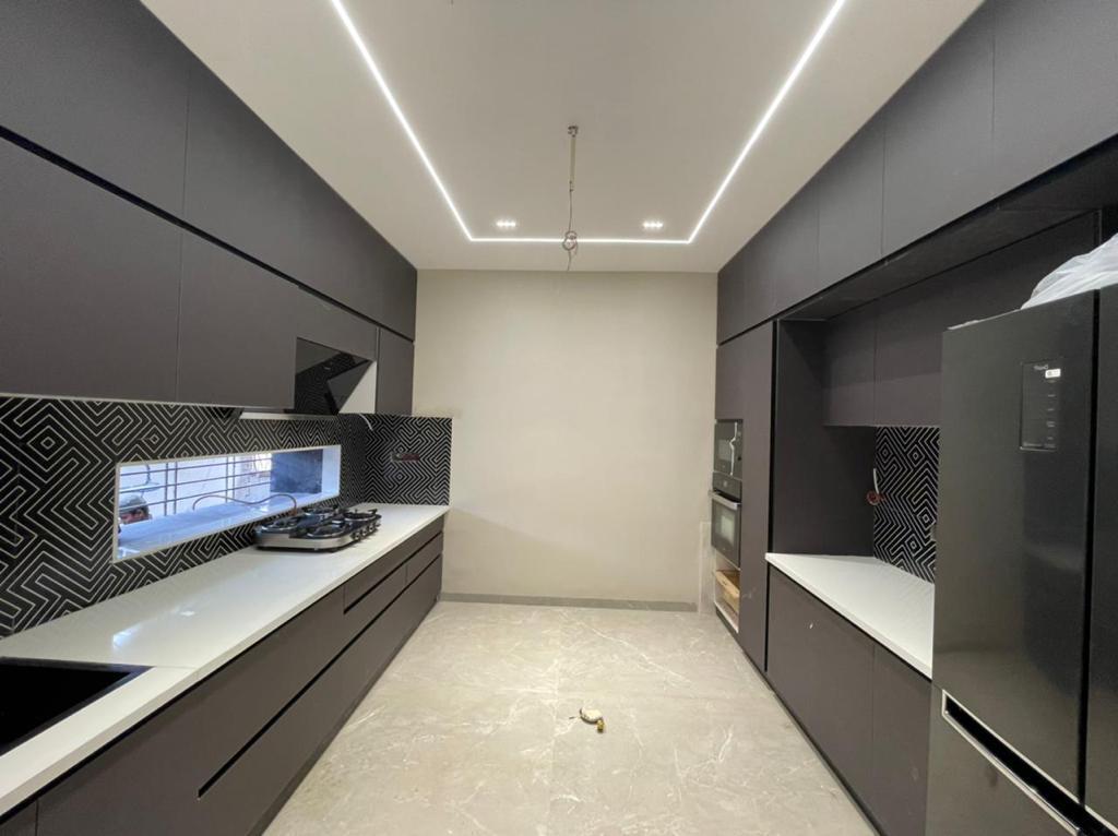 Parallel modular kitchen in Aurangabad with mocha shutters, geometric backsplash and tall storage by More Than Kitchen